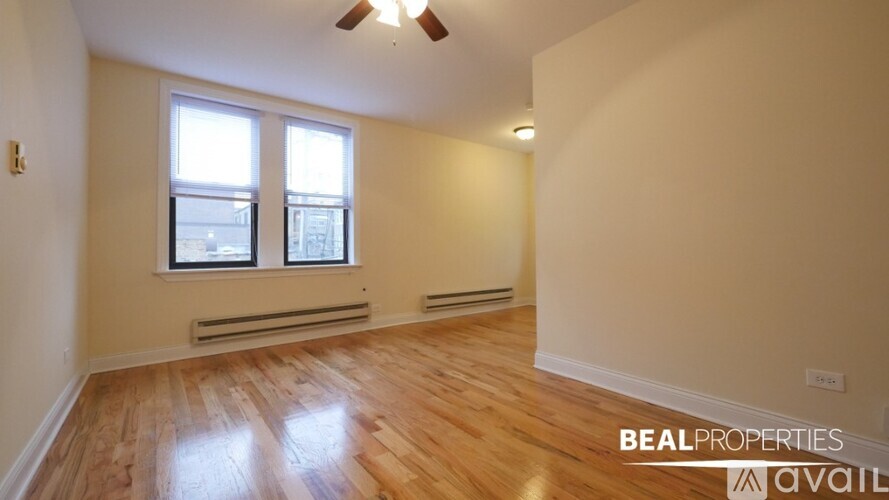 A room with wooden flooring and a window with a view of buildings outside.
