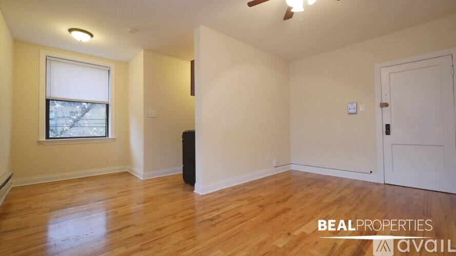 A room with wooden floors and a window with a view of a tree.