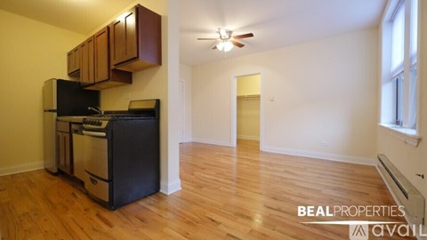 A kitchen area with wooden cabinets and a black fridge.