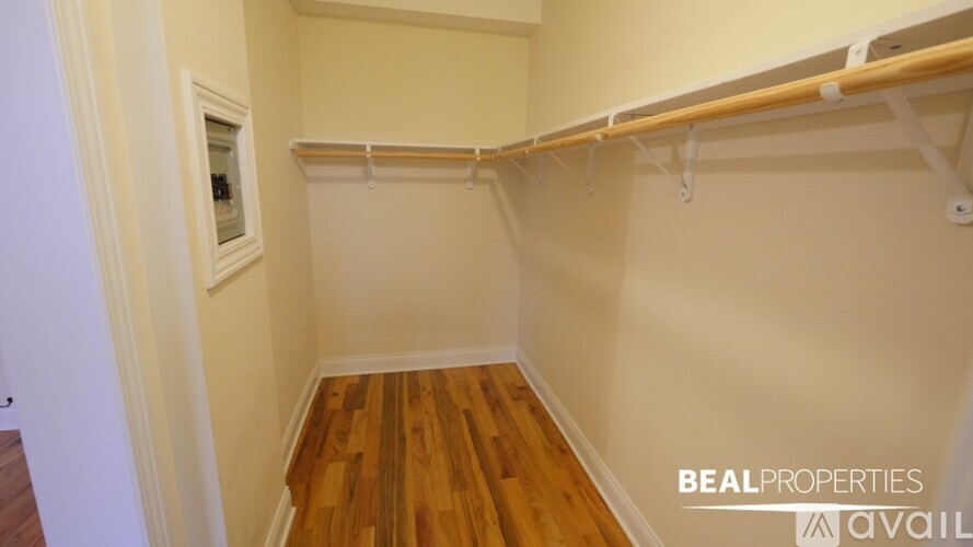 A small, empty room with a wooden floor and a white wall.