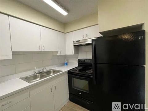 A black refrigerator is in a kitchen with white cabinets.