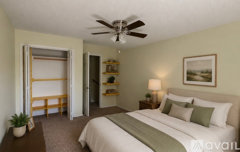 A bedroom with a large bed, a ceiling fan, and a painting on the wall.