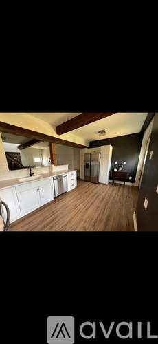 A spacious room with wooden floors and a large window.