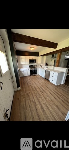 A kitchen with white cabinets and a wooden floor.