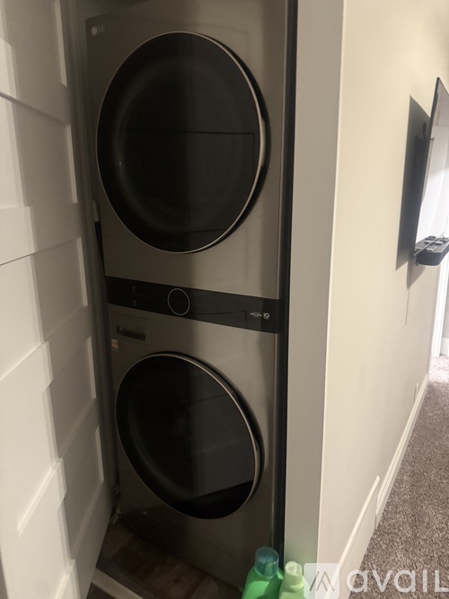 A washing machine is in a small space between a wall and a door.