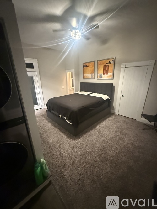 A bedroom with a bed, a ceiling fan, and two pictures on the wall.