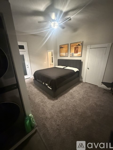 A bedroom with a bed, a ceiling fan, and two pictures on the wall.