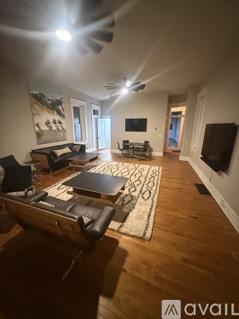 A living room with a black leather couch and a rug.