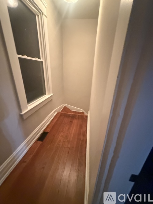 A hallway with a wooden floor and white walls.