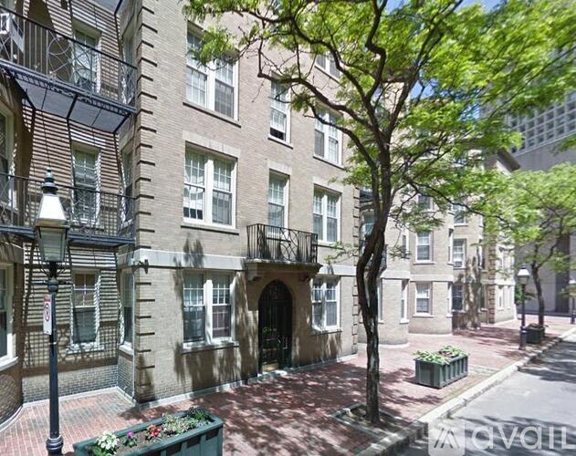 A tree in front of a building with a balcony.