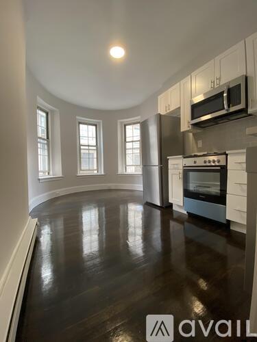 A kitchen with a wood floor and white walls.