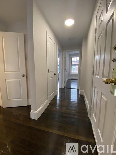 A hallway with white doors and a wooden floor.