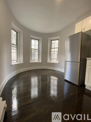A kitchen with a refrigerator and wooden floors.