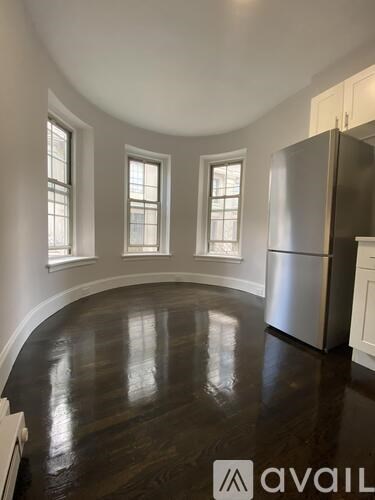 A kitchen with a refrigerator and wooden floors.