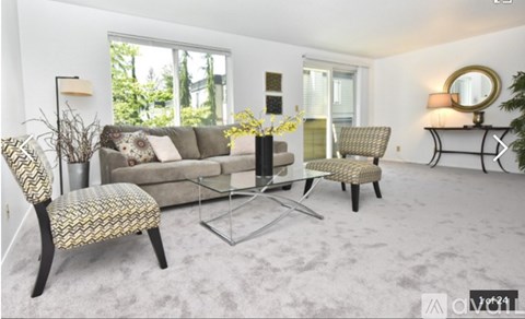 A living room with a grey sofa, two chairs and a glass coffee table.