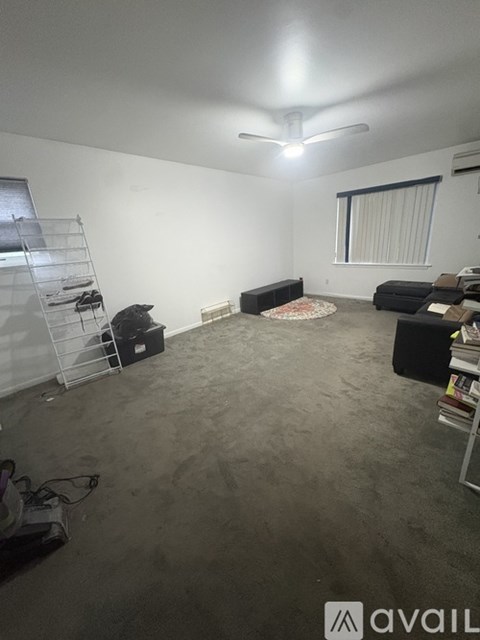 A room with a ceiling fan and a window with blinds.