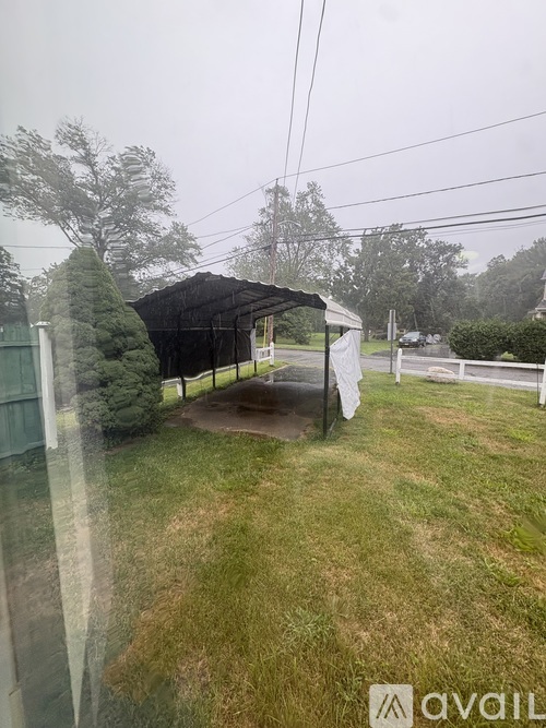A patio area with a black awning and a white fence.