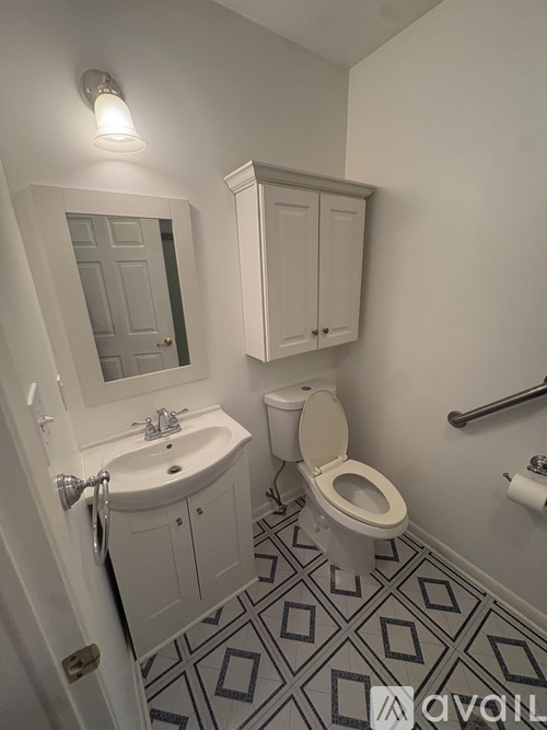 A bathroom with a toilet, sink, and mirror.