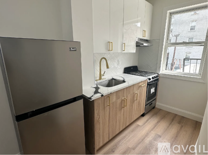 A kitchen with a stainless steel refrigerator and wooden cabinets.