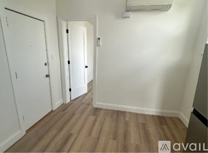 A hallway with a white door and a wooden floor.