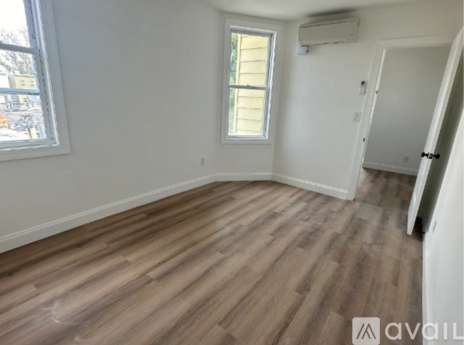A room with wooden flooring and a window with blinds.
