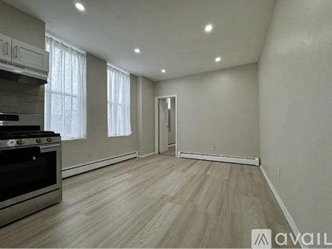 A kitchen with a stove top oven and a wooden floor.
