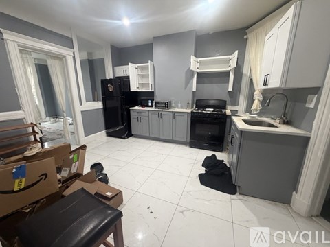 A kitchen with a black fridge and stove, a sink, and a dining table with chairs.