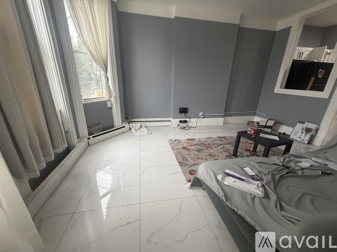 A bedroom with a large bed and a window with curtains.