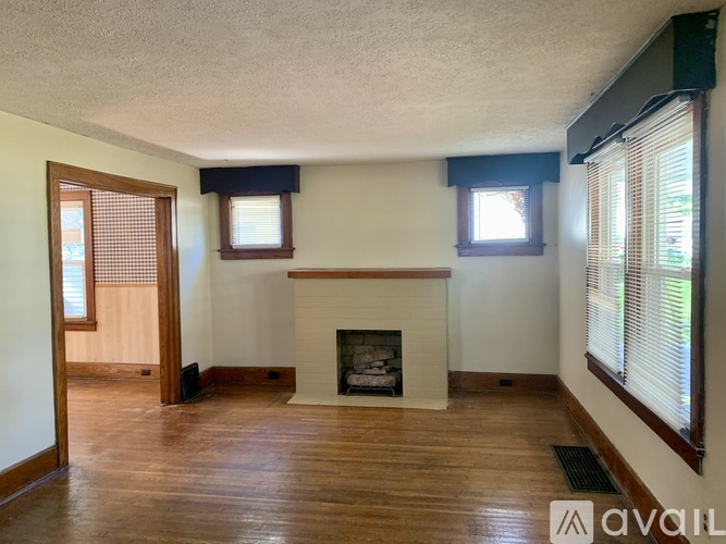 A living room with a fireplace and two windows.