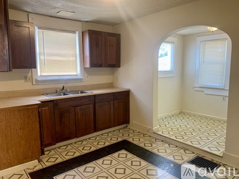 A kitchen with wooden cabinets and a black and white tiled floor.