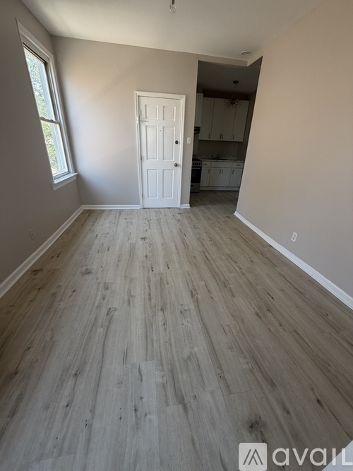 A room with wooden flooring and a white door.