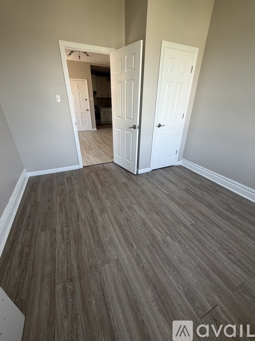 A room with a wooden floor and two white doors.