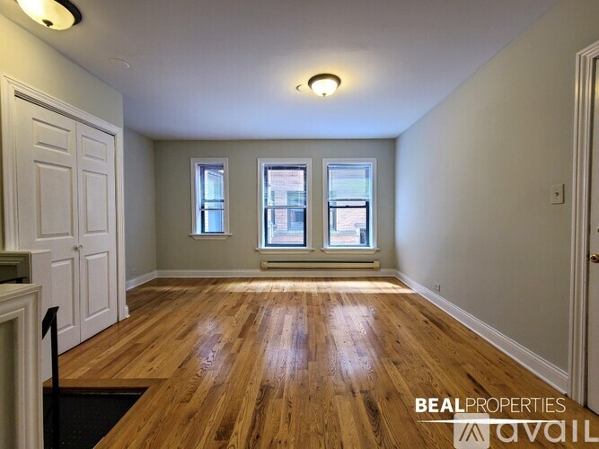 A room with wooden floors and two windows.