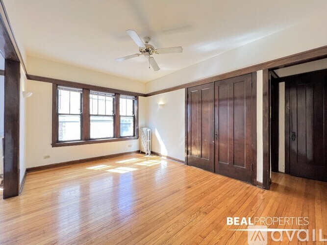 A spacious room with wooden floors and a ceiling fan.