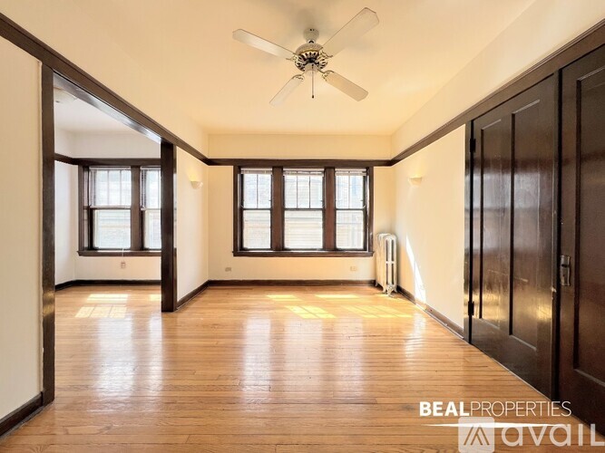 A spacious room with wooden floors and a ceiling fan.