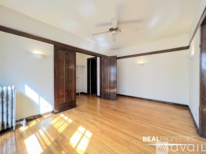 A spacious room with wooden floors and a ceiling fan.