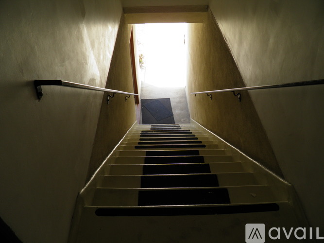 A staircase with a black carpeted stairway leading to a bright light at the end.
