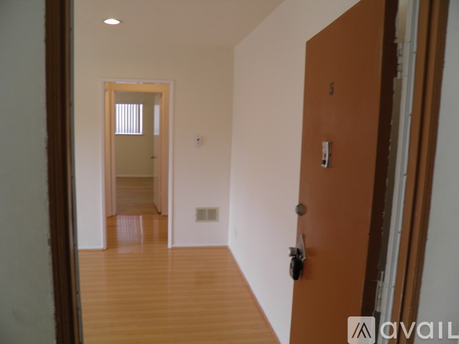 A hallway with a brown door and a white wall.