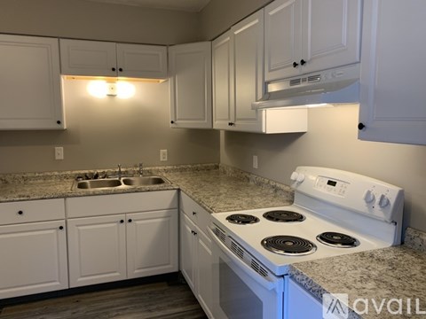A kitchen with white cabinets and a white stove top oven.