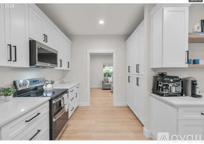 A kitchen with white cabinets and appliances, a stove, and a microwave.