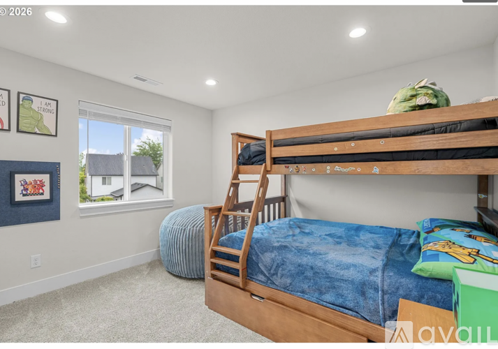 A bedroom with a bunk bed and a window overlooking a house.