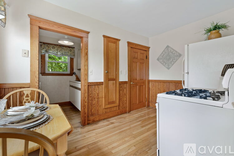 A kitchen with a white stove top oven and wooden floors.