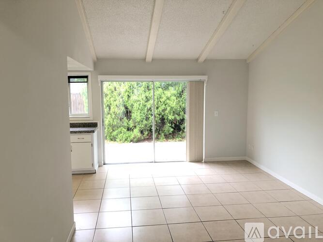 A room with white walls and tiled floor with a window and sliding glass door.