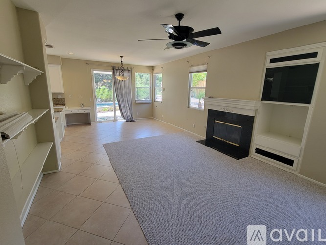 A spacious living room with a fireplace and a ceiling fan.