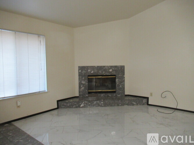 A living room with a fireplace and a window with blinds.