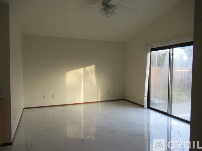 A spacious room with a ceiling fan and sliding glass doors.