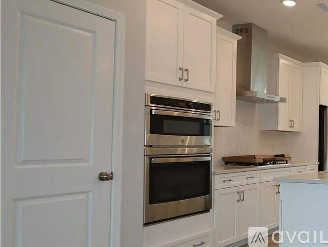 A modern kitchen with white cabinets and stainless steel appliances.