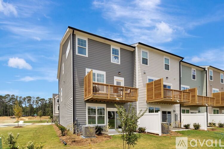 A modern two-story apartment building with balconies and a clear blue sky.