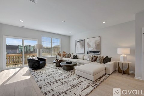 A spacious living room with a large sofa set, a coffee table, and a view of the outdoors through the windows.