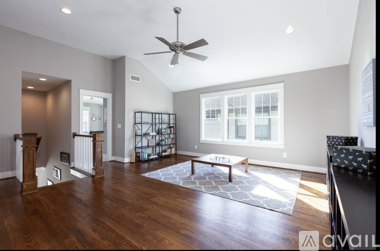 A spacious living room with a ceiling fan and hardwood floors.